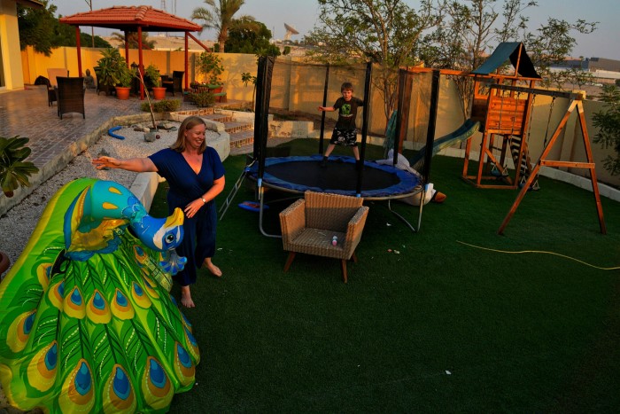 Donna Dickinson moves a peacock pool float as her 7-year-old son Elliot Dickinson jumps on a trampoline in the backyard of their home in Jebel Ali Village in Dubai, United Arab Emirates, on Tuesday November 2 2021