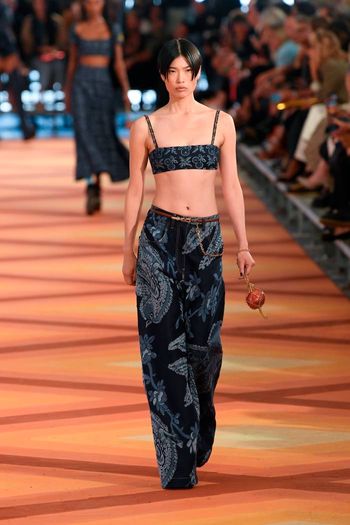 A catwalk model wears loose patterned pants with a bandeau top