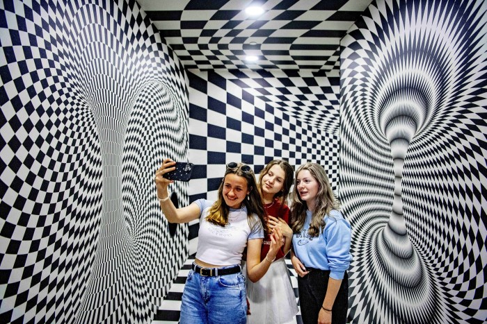 Female TikTokkers pose in an optical illusion room