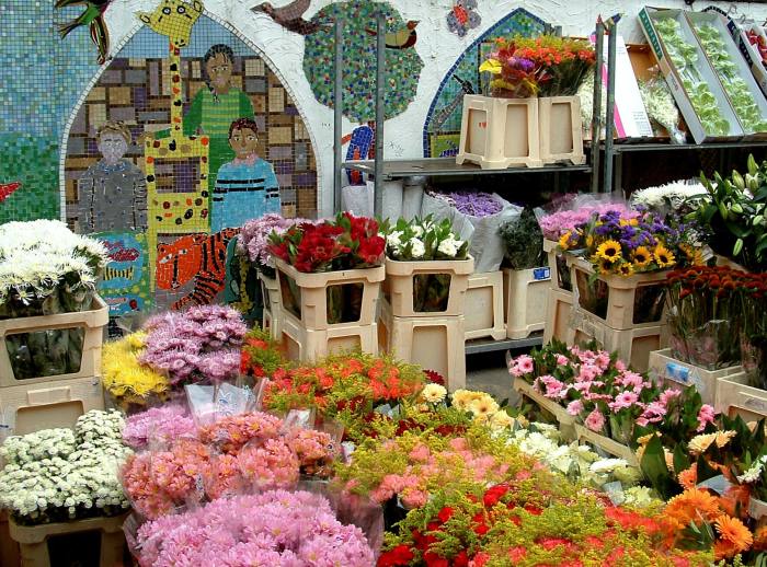 Stalls selling flowers in front of a mosaic at the Columbia Road Flower Market