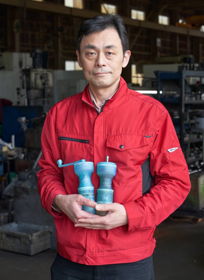 Kimihiko Yamashita, the new owner of Araie Manufacturing, holding two coffee mills, which the company is looking to produce