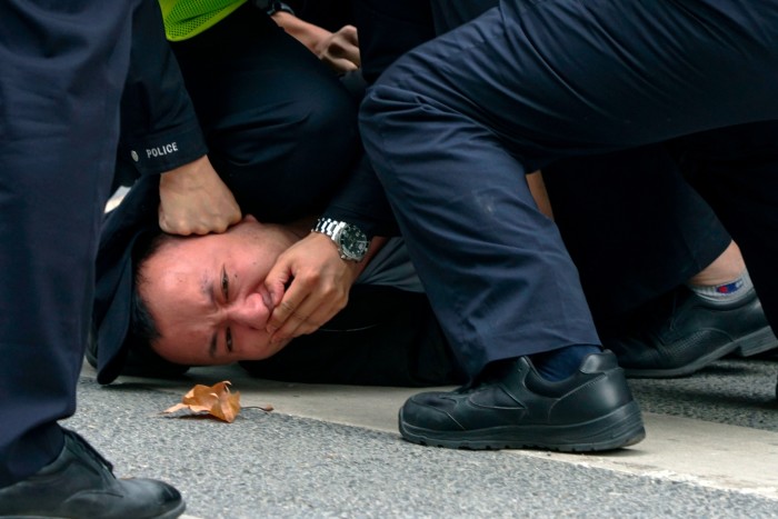 A protester is detained by police in Shanghai on Sunday