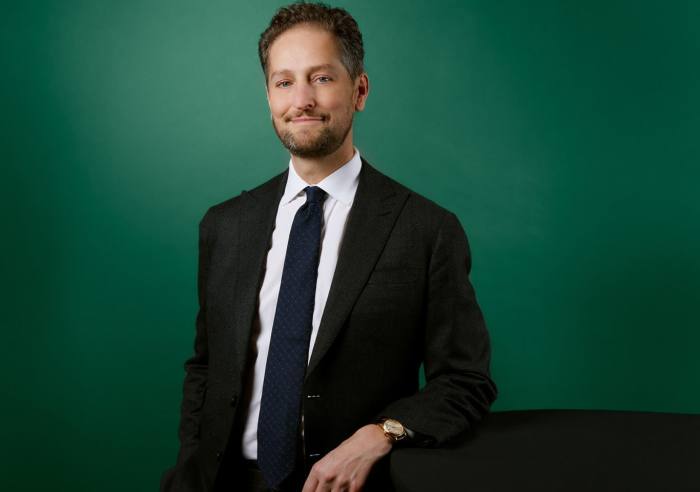 Smiling photo of Noah Horowitz standing in a dark suit and tie