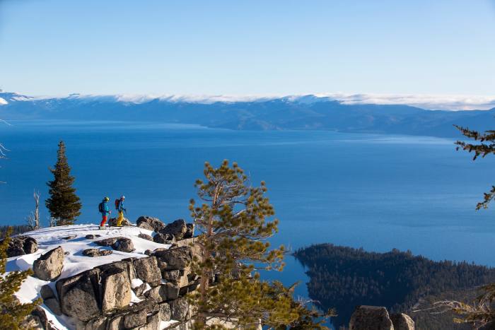 Two people standing on a peak overlooking Lake Tahoe