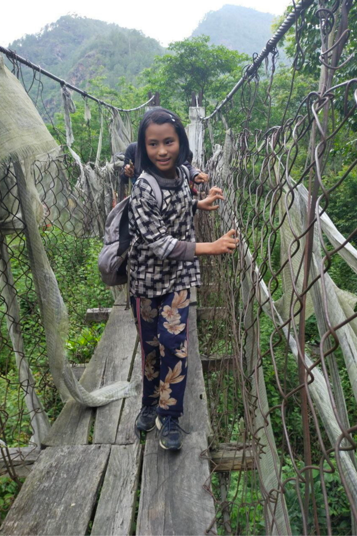 A young girl stands on a rope bridge