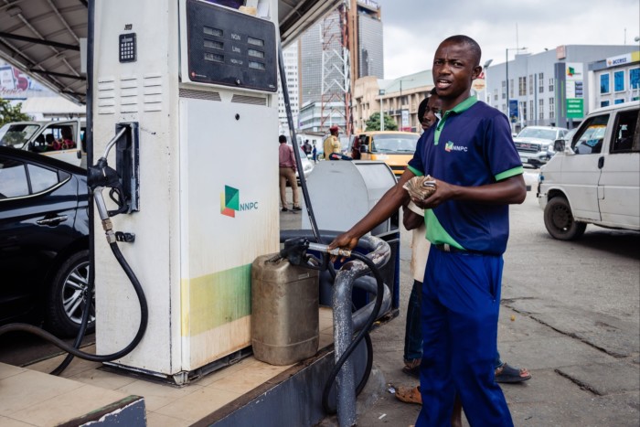 A fuel attendant fills a container with fuel for a customer at a Nigerian National Petroleum Company