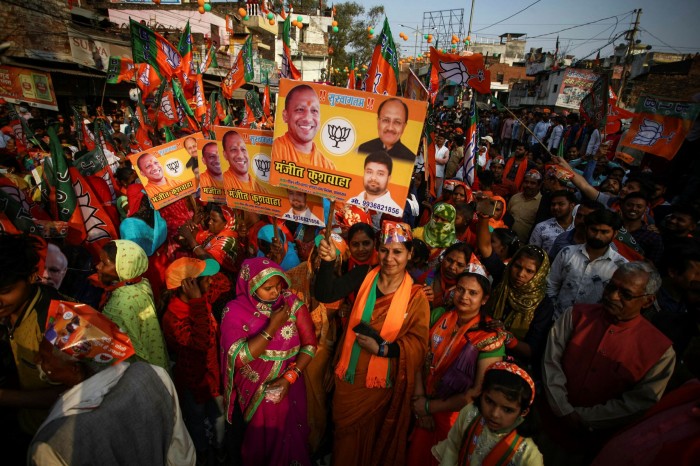 Supporters of Uttar Pradesh chief minister Yogi Adityanath hold banners with his face on it 