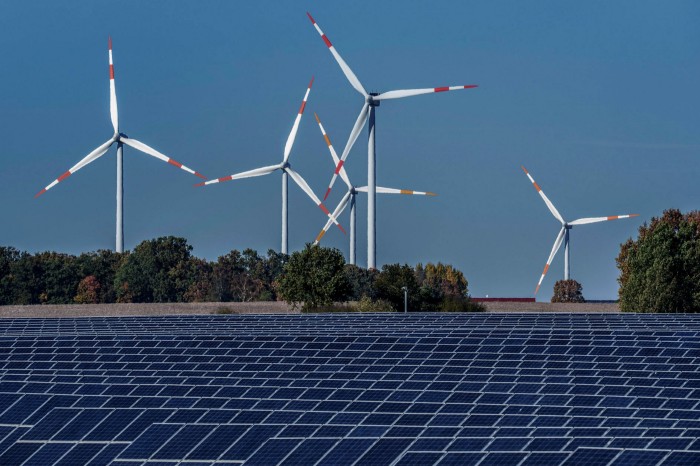 Wind turbines turn behind a solar farm