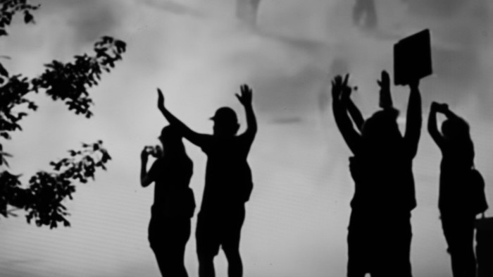 Silhouettes of people holding their hands up