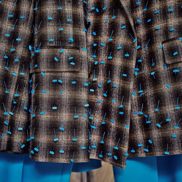 Checkered jacket detail, in light and dark brown with cerulean-coloured bead-like accents 