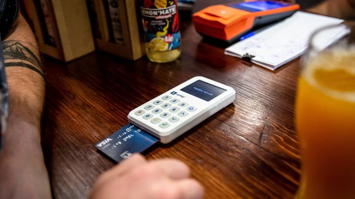 A credit card is inserted into a card reader  placed on top of a table