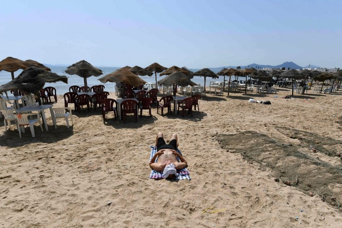 Un homme allongé sur une plage presque déserte de Tunis lors d'un confinement imposé par les autorités tunisiennes