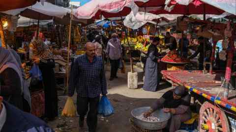 A shopper walks through a food market in Alexandria, Egypt