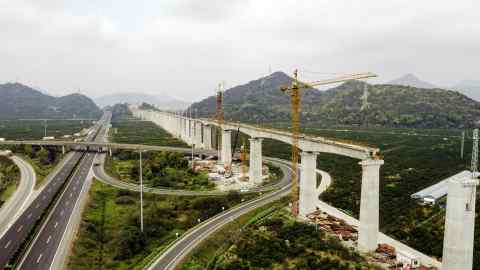 A highway runs next to an under-construction section of elevated track for China State Railway Group in Taizhou, China