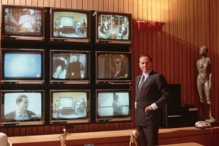 Berlusconi beside an array of televisions