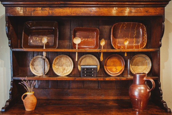 An 18th-century Welsh oak dresser, £7,250. Top shelf: Welsh Buckley-pottery slipware dishes, from £350. Middle shelf: five 19th-century sycamore plates, from £265 each, a pair of Welsh tin “hog-scraper” candlesticks, £395, and a miniature 19th-century slate model of a bureau, £225. Bottom shelf, from left: a small 19th-century earthenware jug, £350, and a 19th-century stoneware jug, £475