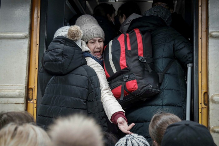 A woman reaches her hand back to someone as people try to board a train at Kyiv station