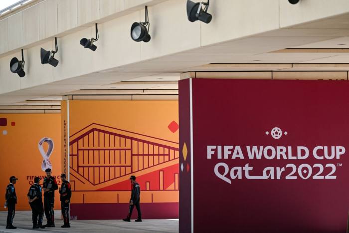 Police officers stand near FIFA World Cup signs outside the main media center in Doha
