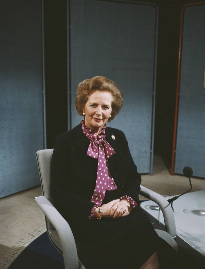 Mrs Thatcher, seated, wears a purple pussy bow, one of her trademark accessories