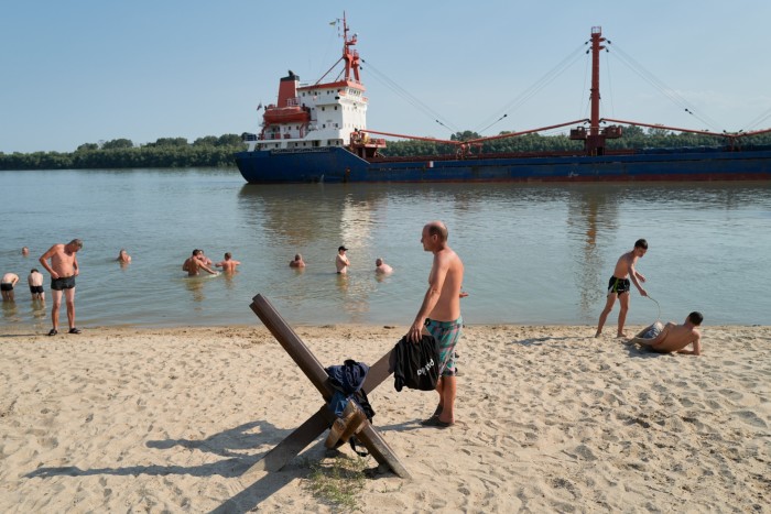 People sit on a public beach and swim in the Danube river