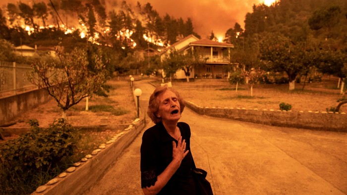 A resident reacts as a wildfire approaches her house on the island of Evia, Greece, on Sunday