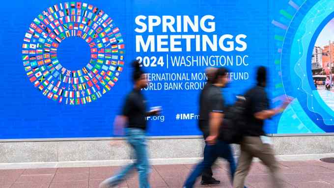 Pedestrians walk past the IMF headquarters in Washington on Friday