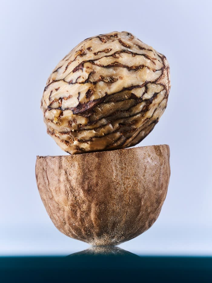 A nutmeg kernel sits atop half of its outer coating