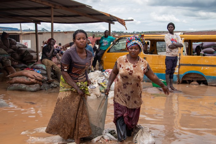 African miners tread through muddy flood waters