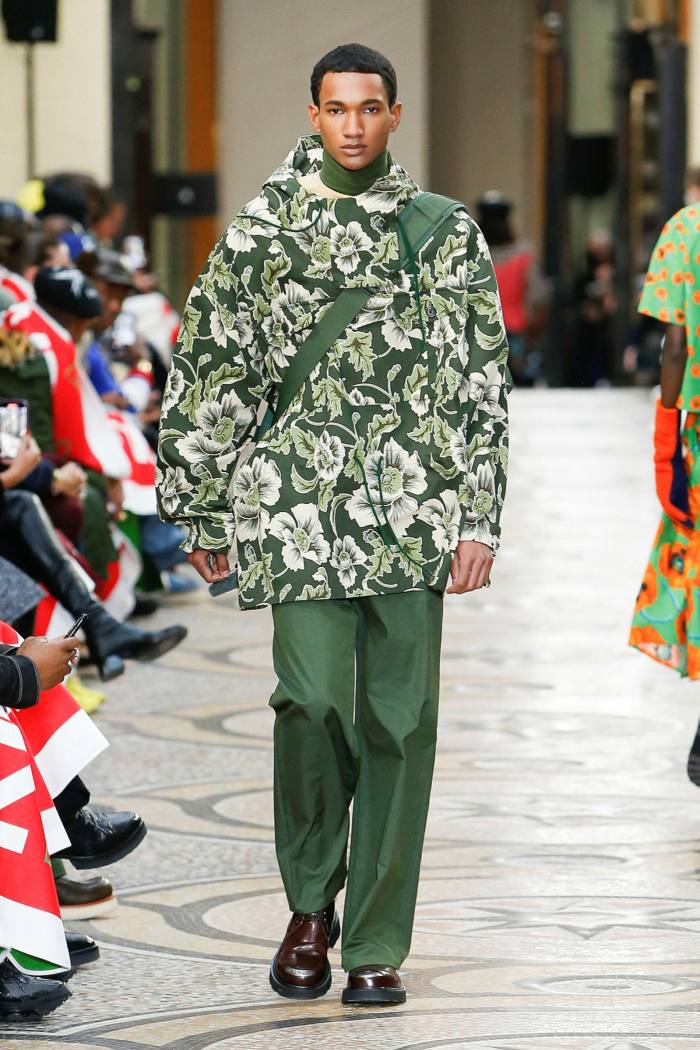 A male model in green trousers and green and white parka-style jacket