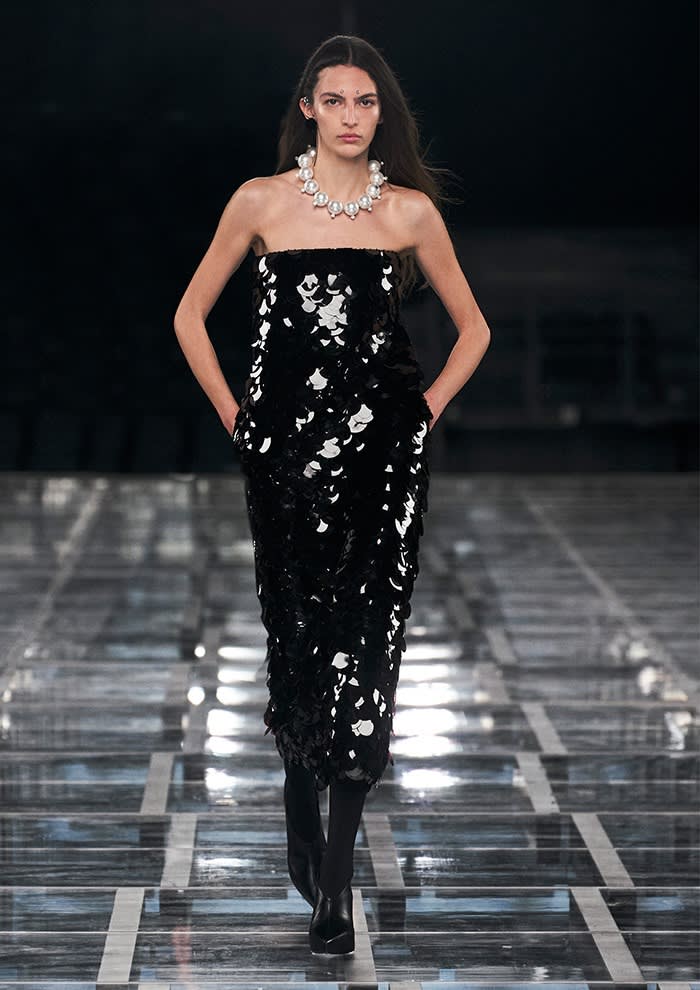 A female model wears a long, tight-fitting sparkly black dress