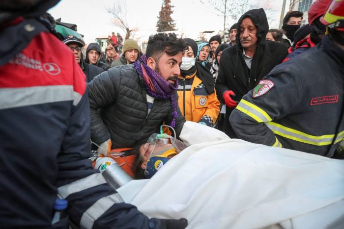 Rescuers carry a survivor from a collapsed building in the aftermath of a deadly earthquake in Adiyaman, Turkey