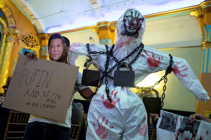An antiwar protester in the US holds a poster accusing Xi and Putin of being war criminals over the invasion of Ukraine