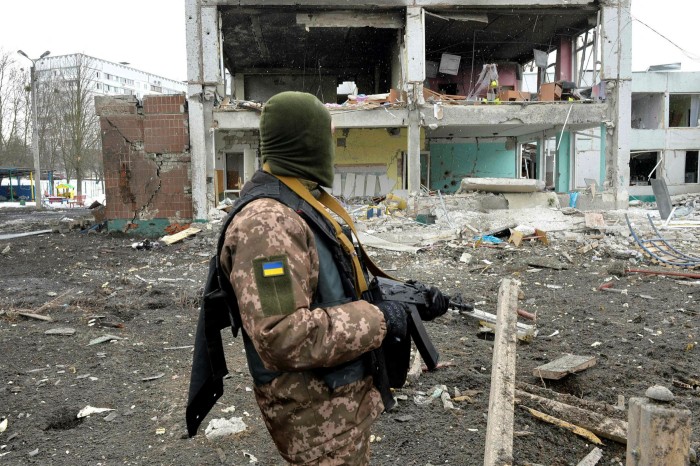 A member of the Ukrainian Territorial Defense Forces looks at the damage following a shelling in Ukraine's second-largest city of Kharkiv