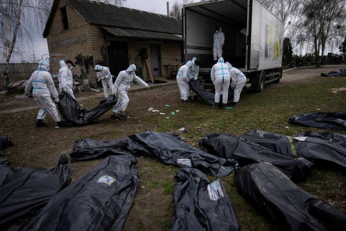Volunteers load on to a truck the bodies of civilians killed by Russian soldiers in Bucha, Ukraine