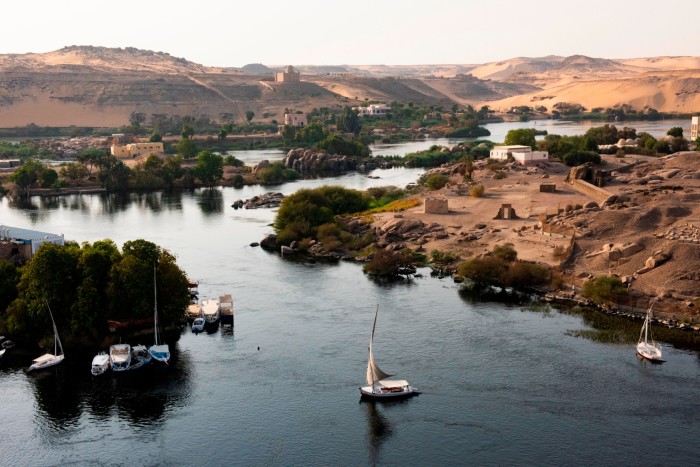 An overhead view of the river Nile with small sail boats and monuments on the riverbank 