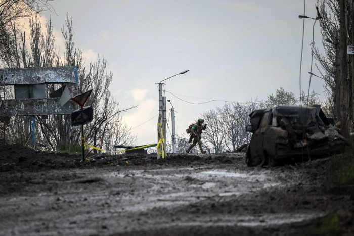 A Ukrainian serviceman runs for cover from shelling across a street in Bakhmut, Donetsk region in April