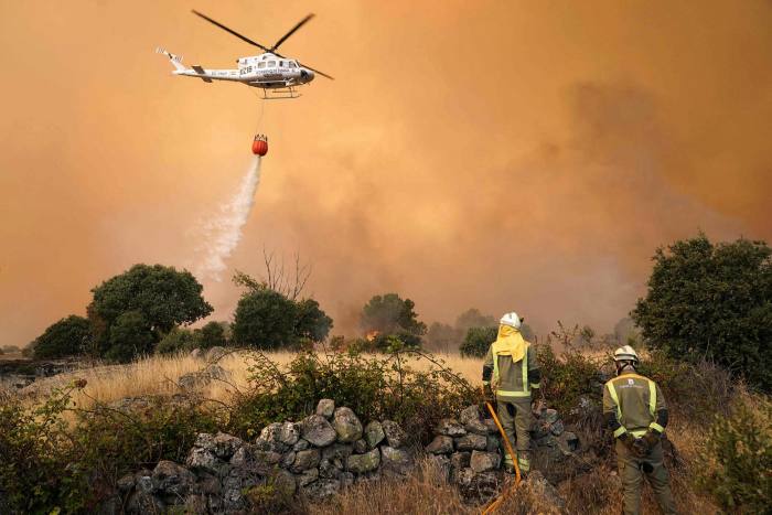 A helicopter drops water as fires rage in Navalmoral de la Sierra near Avila, Spain on August 16