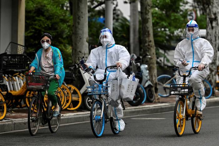 Health workers cycle on a street in Shanghai’s Jing’an district on Sunday