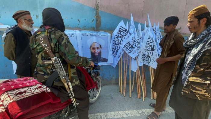 Taliban forces gather around a poster showing Afghanistan’s supreme leader Haibatullah Akhundzada