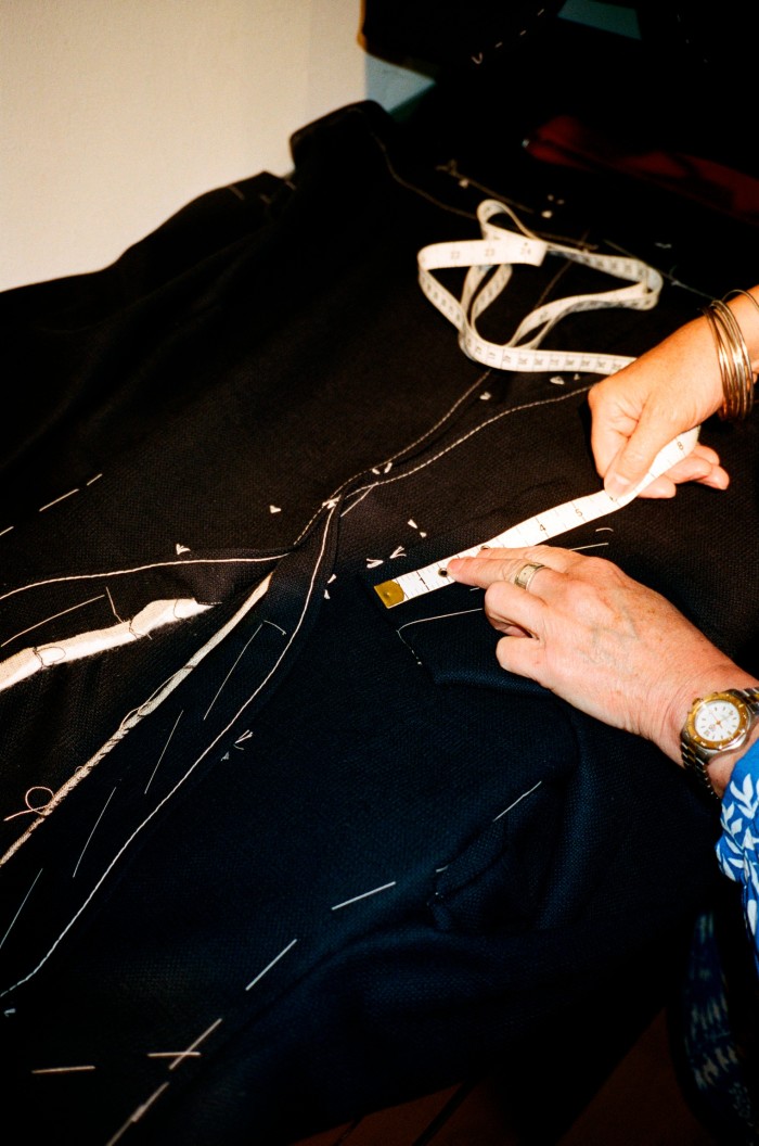 The hands of a tailor measuring and cutting the fabric on a suit jacket