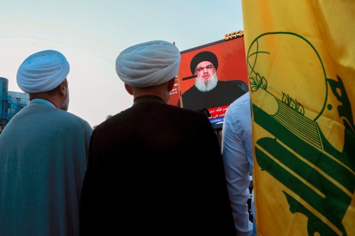 Iraqi demonstrators watch a televised speech from Lebanon’s militant Hizbollah leader Hassan Nasrallah at a pro-Palestinian rally in Iraq
