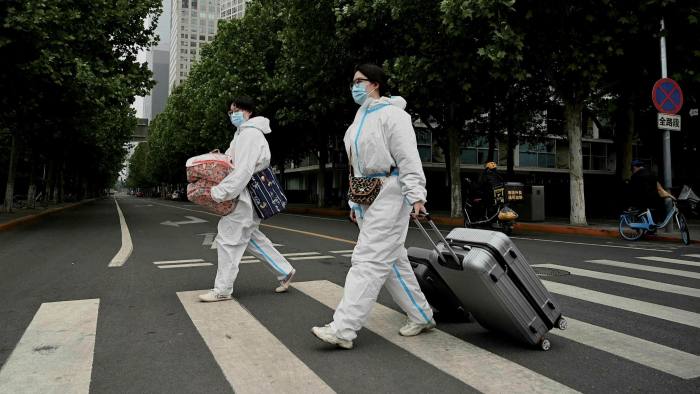 People wearing personal protective equipment cross a street in Beijing on Tuesday 