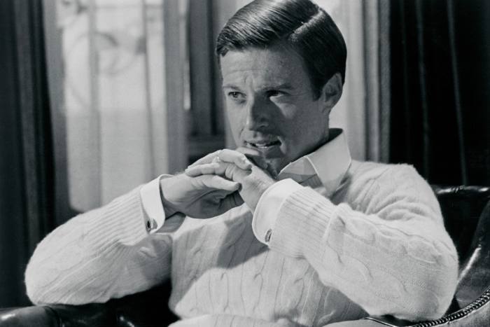Robert Redford, seated and with hands clasped touching his chin, in a scene from ‘The Great Gatsby’