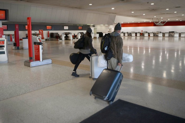 Des passagers traversent un terminal Qantas presque désert à l'aéroport international de Melbourne