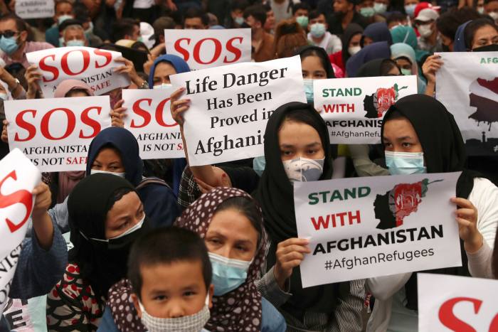 Afghan refugees, mostly members of the Hazara ethnic minority, hold posters during a rally outside the UN refugee agency office in Jakarta, Indonesia