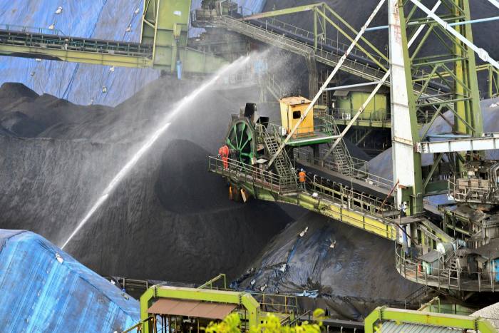 Water is sprayed onto a shipment of coal after being unloaded from a cargo vessel at the Mormugao Port Trust in Goa