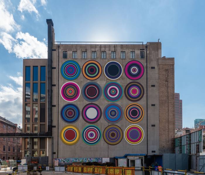 A four by four grid of large colourful circles on the side of a building