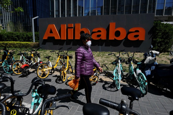 A woman walks past an Alibaba sign outside the company's office in Beijing, China