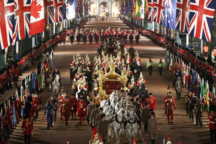 A gold coach and uniformed military line a London street at night to rehearse the coronation ceremony