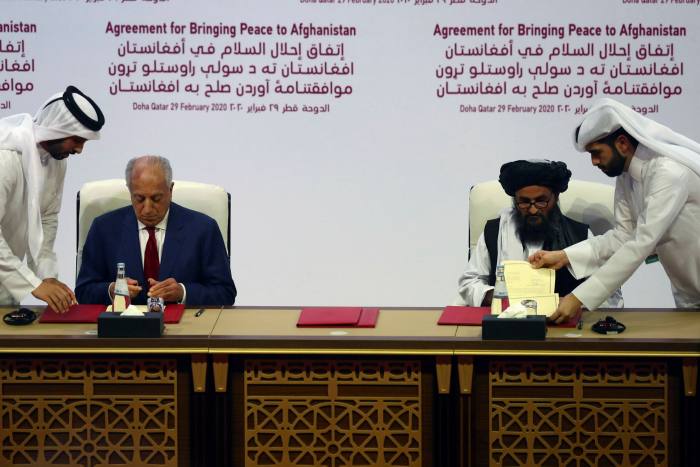 Abdul Ghani Baradar, right, leader of the Taliban delegation, signs an agreement with Zalmay Khalilzad in Doha, Qatar, on February 29 2020